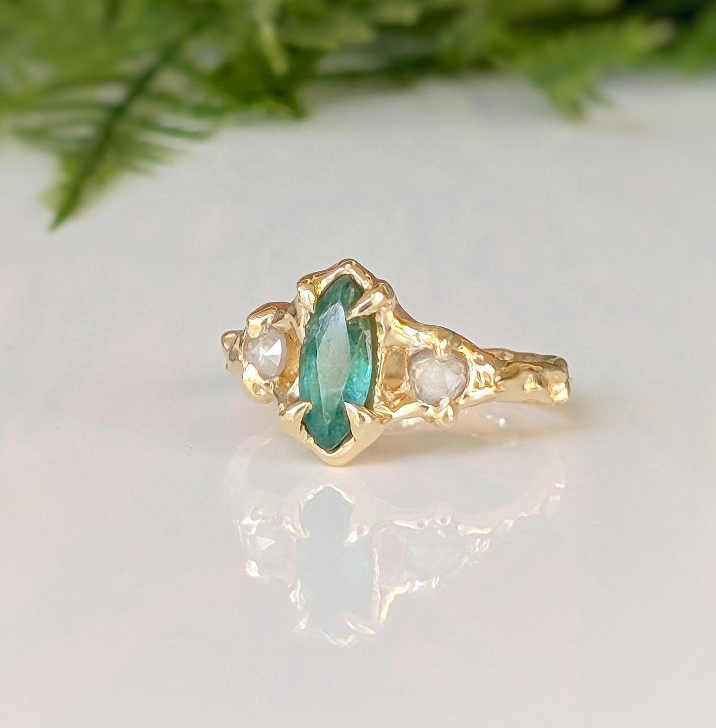 Emerald and diamond engagement ring in 14k gold with marquise cut emerald and salt & pepper diamonds.