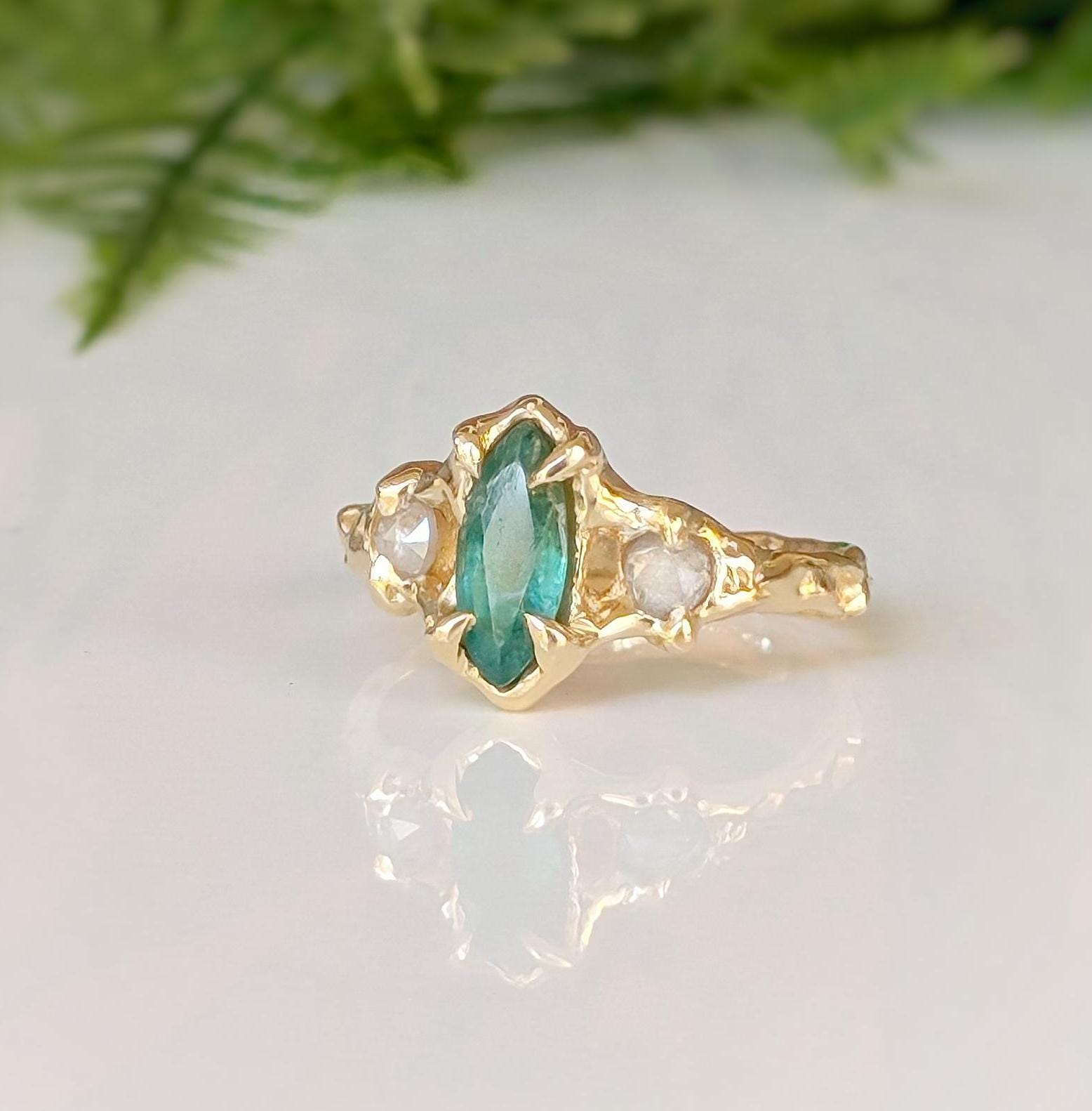 Emerald and diamond engagement ring in 14k gold with marquise cut emerald and salt & pepper diamonds.