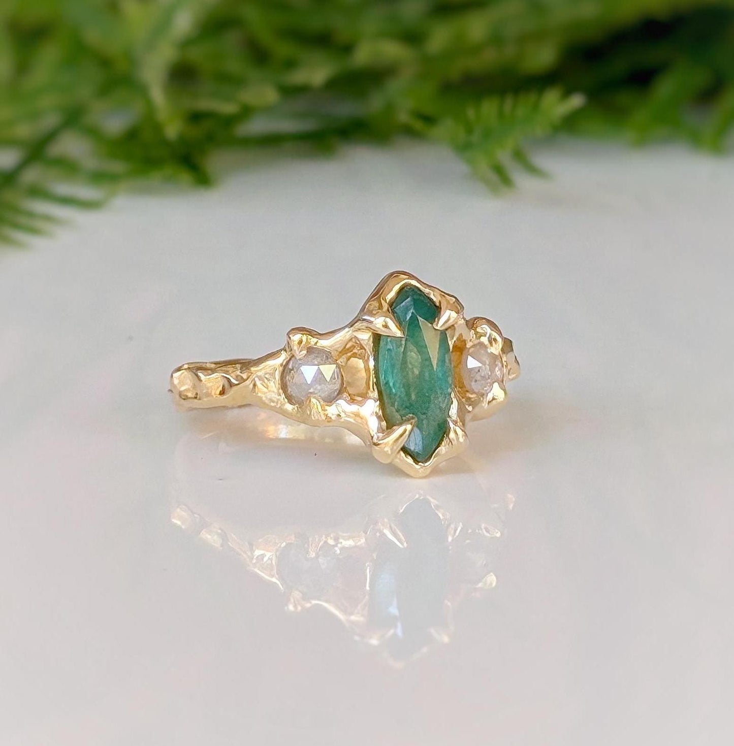 Emerald and diamond engagement ring in solid 14k gold, featuring a marquise cut emerald and salt & pepper diamonds.