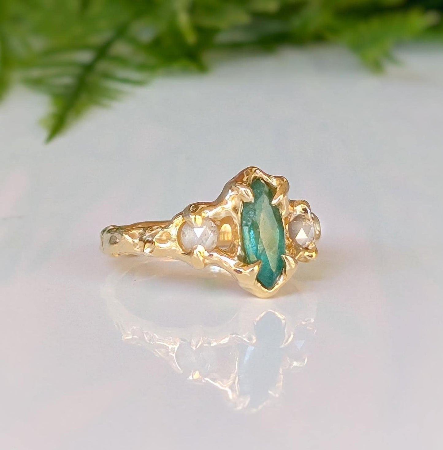 Emerald and diamond engagement ring in 14k gold, featuring a marquise cut emerald and salt & pepper diamonds.