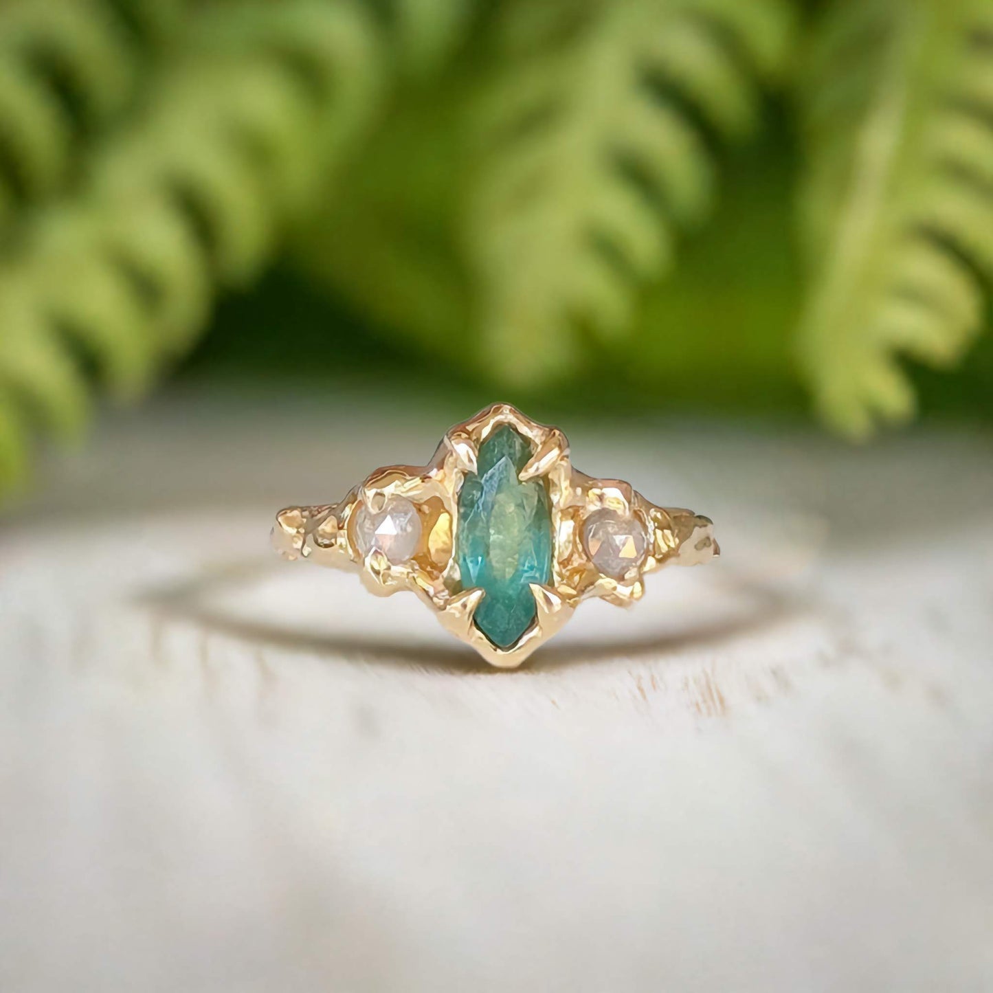 Emerald and diamond engagement ring in 14k gold with marquise cut emerald and salt & pepper diamonds, nature-inspired design.