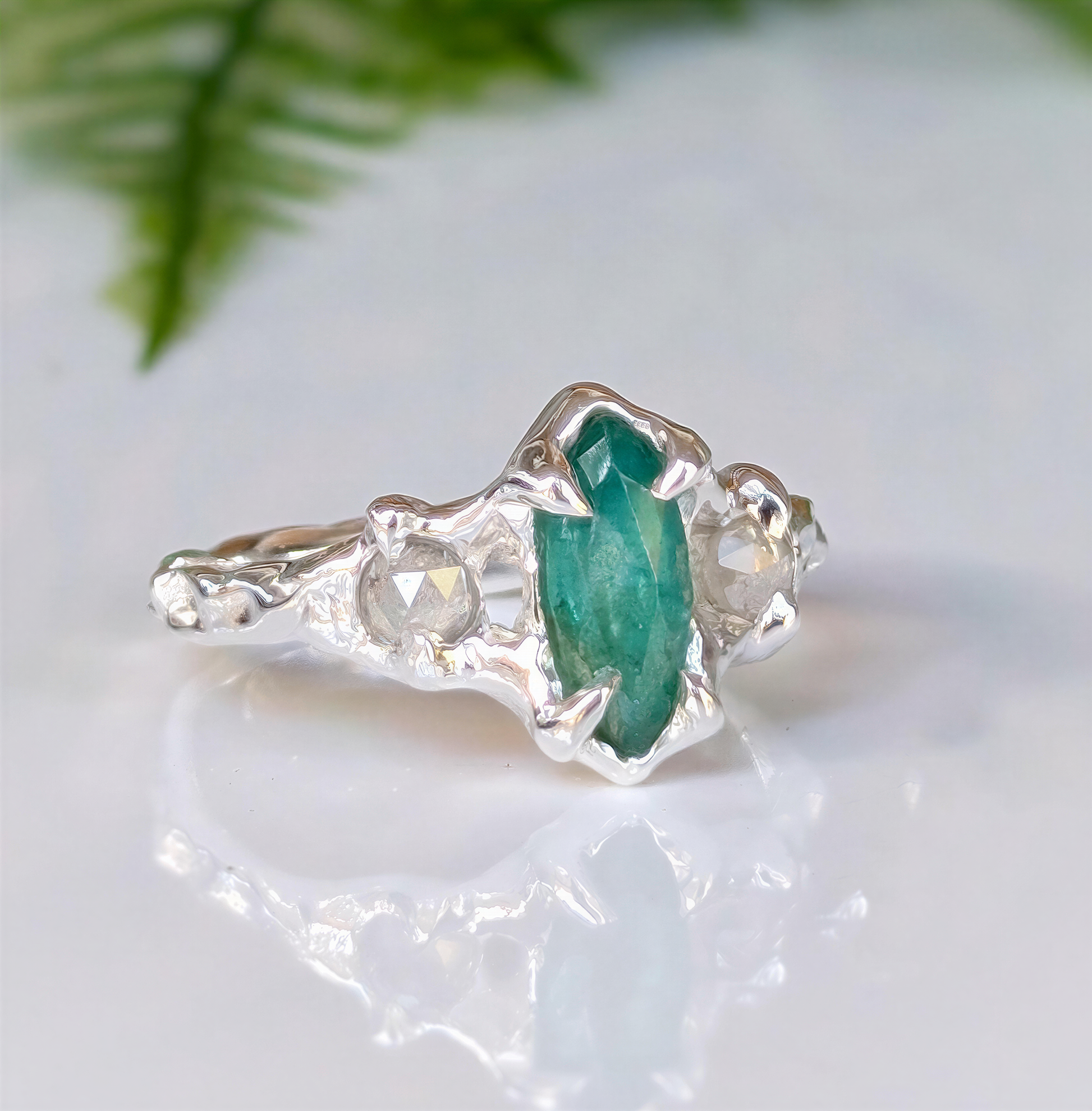 Silver emerald engagement ring with marquise cut emerald and salt & pepper diamonds, nature-inspired design.