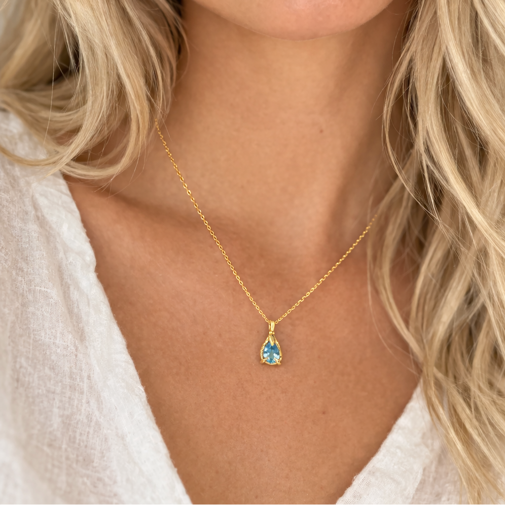 Woman wearing a gold necklace with an Aquamarine gemstone pendant.