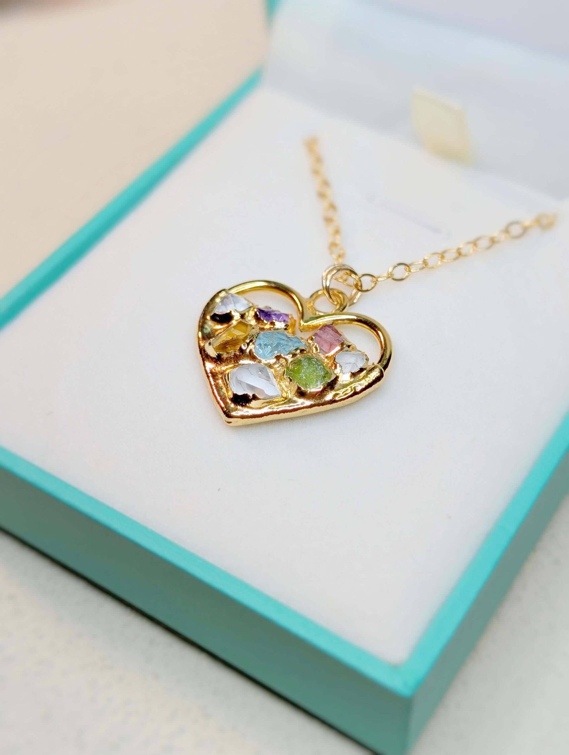 Heart-shaped gold necklace with colorful birthstones in a gift box, perfect personalized gift for mom.