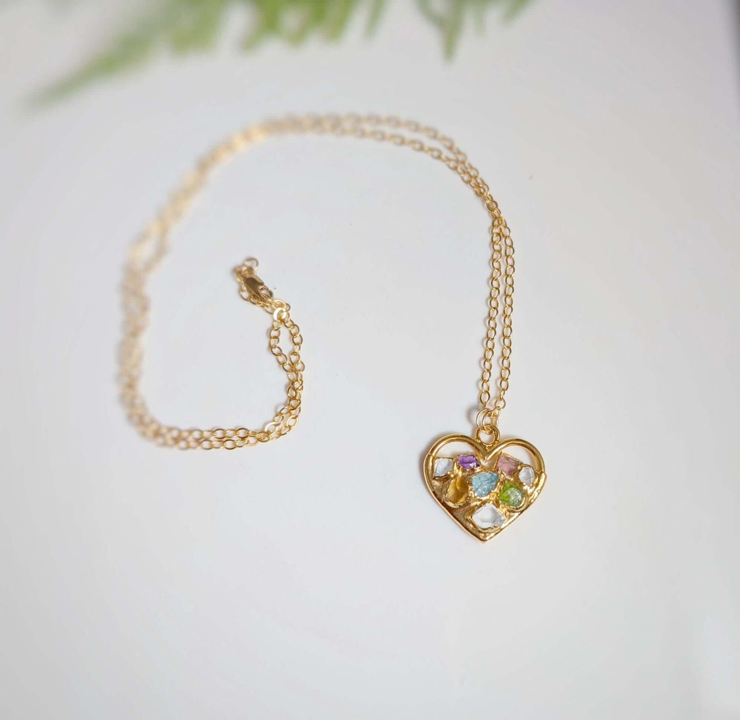 Heart-shaped necklace with colorful birthstones on a gold chain, perfect personalized gift for mom.