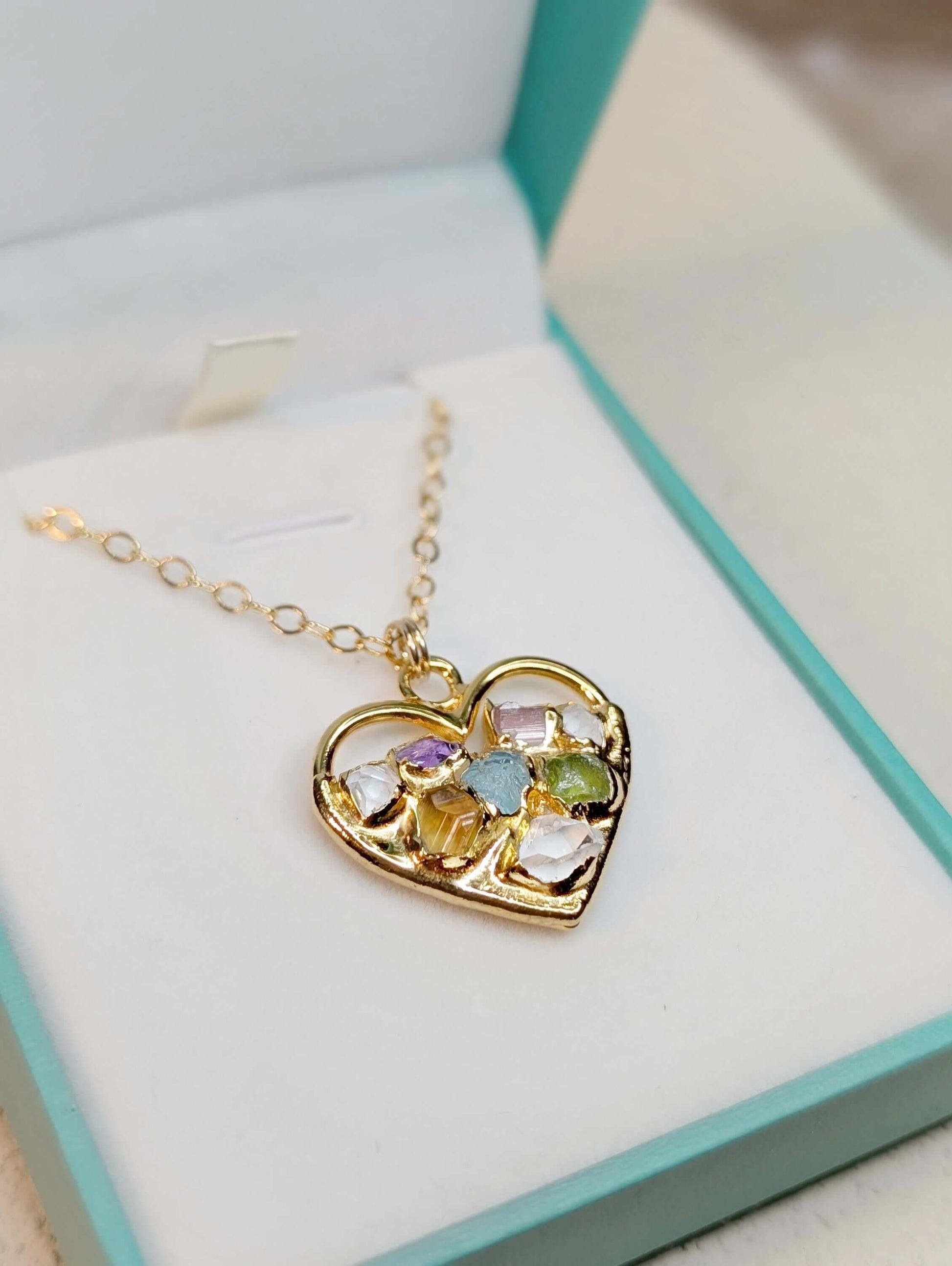 Heart-shaped custom family birthstone necklace in gold with colorful gemstones, displayed in a decorative box.
