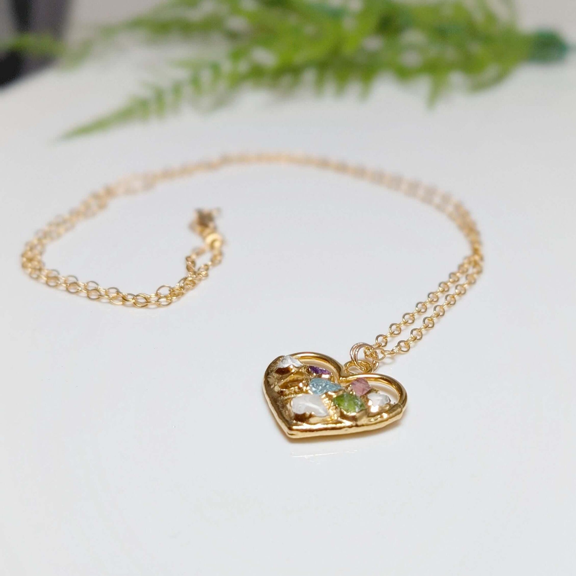 Heart-shaped gold necklace with colorful birthstones, symbolizing family love and connection.
