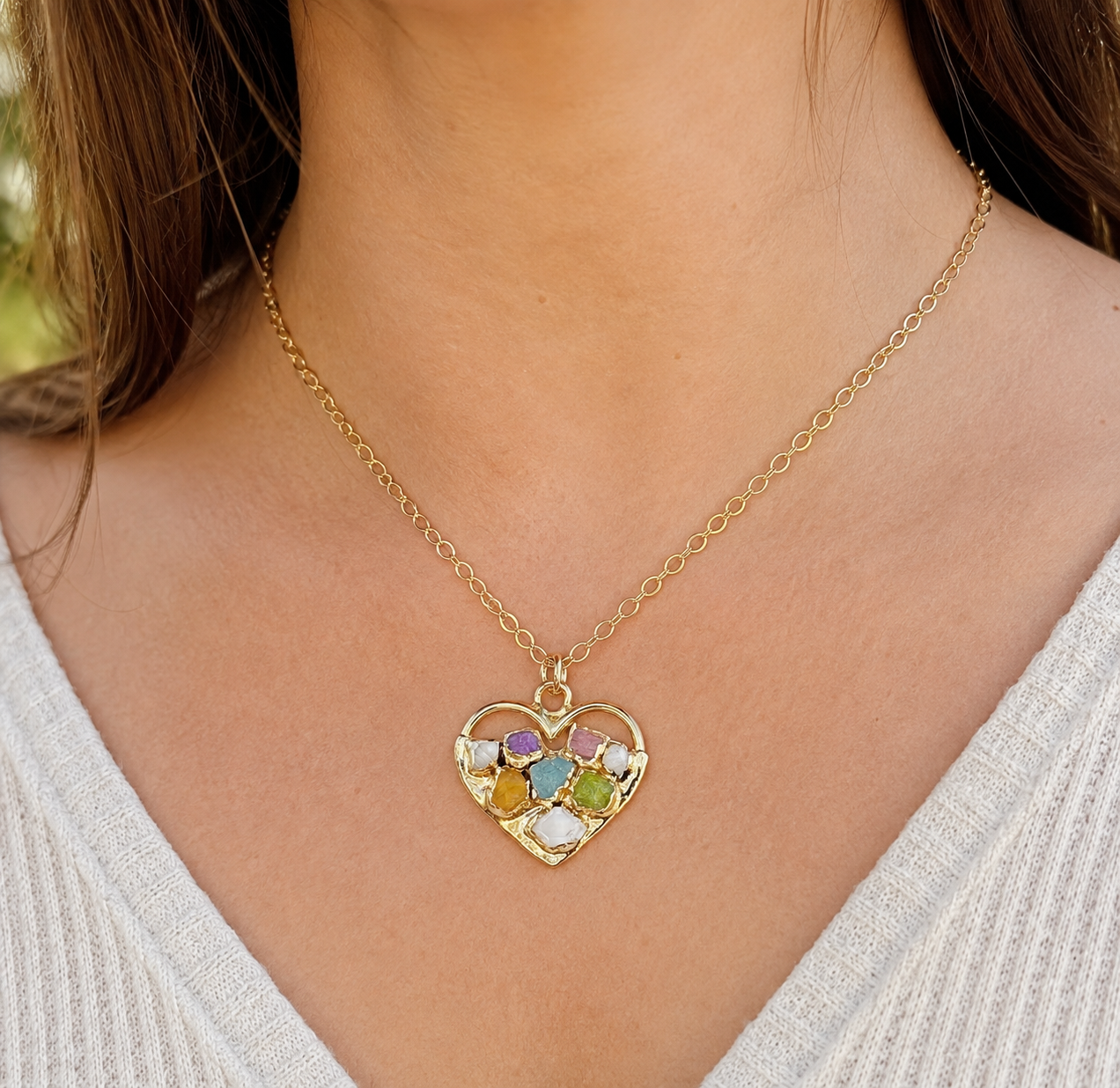 heart shape gold necklace with multi-colour gemstones set around a woman's neck