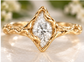 A close-up image of a gold ring with a large Moissanite set in the center, surrounded by a decorative band.