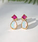 Pair of Gold stud earrings with dark pink Rubies and White Opals on a light background