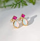 Pair of Gold stud earrings with dark pink Rubies and White Opals on a light background