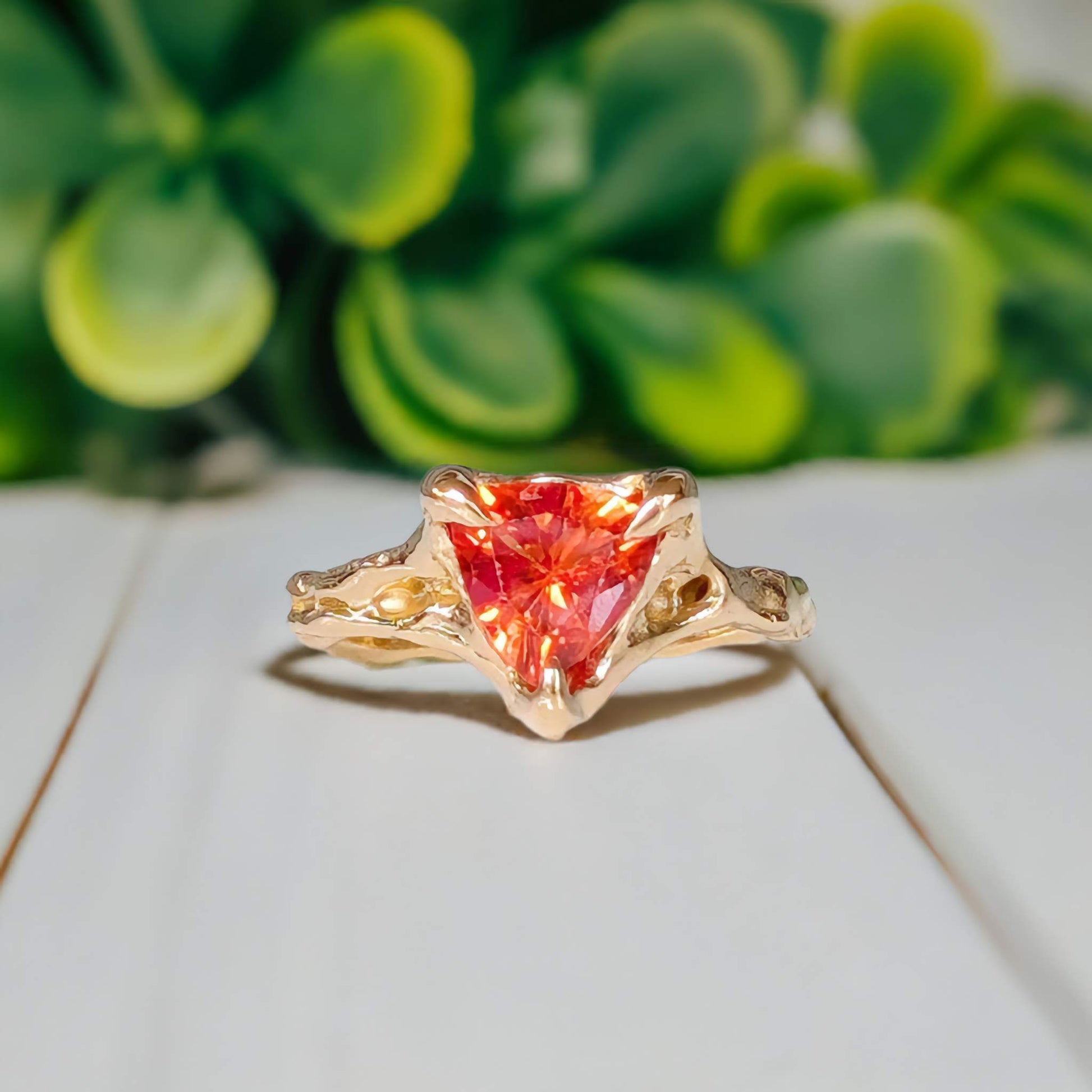 Orange Sapphire trilliant cut ring in textured 14k Gold setting, showcasing a unique handcrafted design.