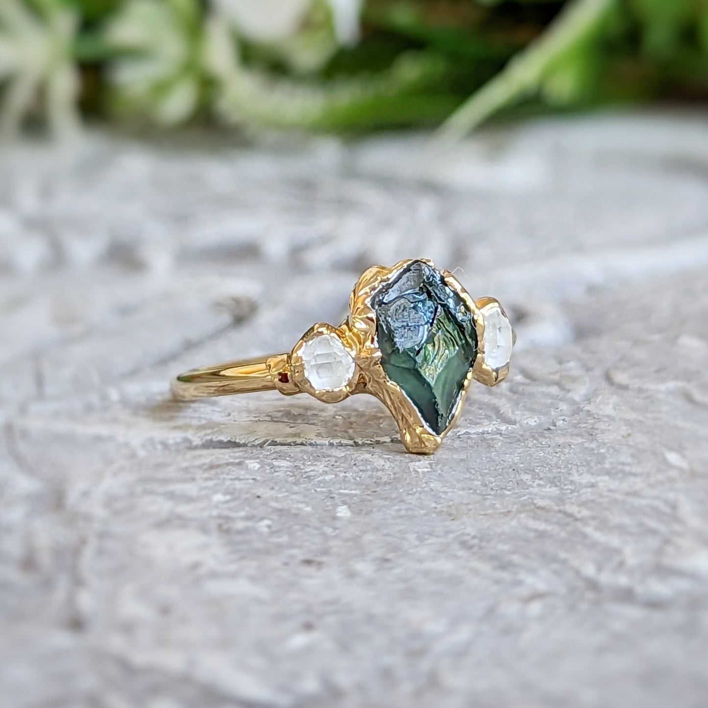 Unique raw green Sapphire and Herkimer diamond engagement ring on a textured surface, designed in 14k gold.