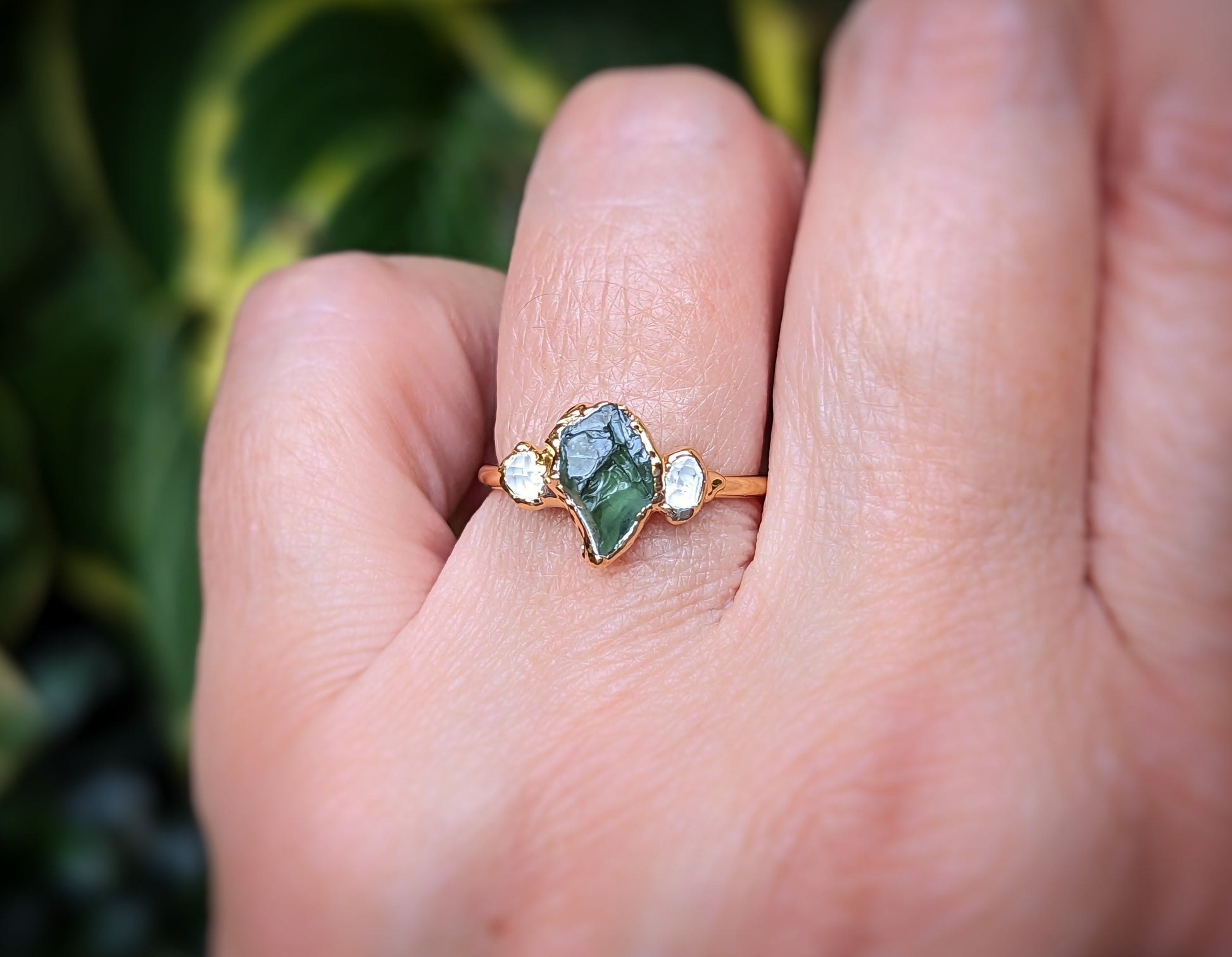 Unique raw green Sapphire engagement ring with Herkimer diamonds, handcrafted in 14k gold, worn on a hand.