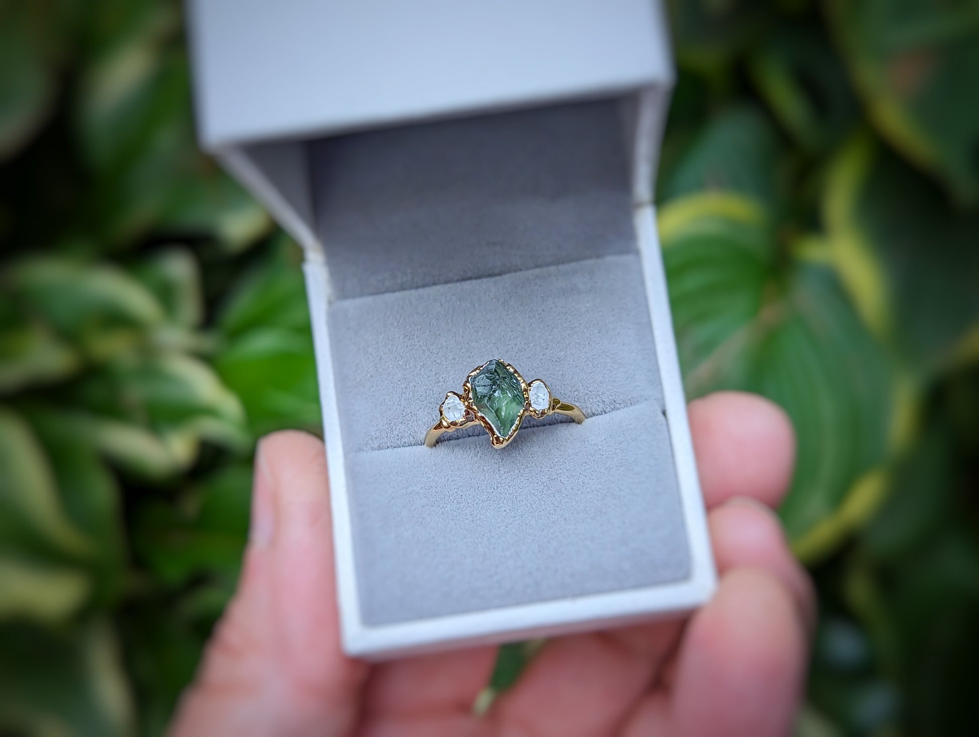 Raw green Sapphire and Herkimer diamond engagement ring in a box, showcasing its unique handcrafted design.