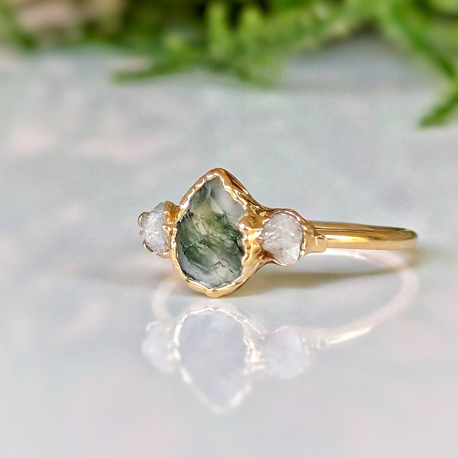 Moss Agate and Herkimer diamond engagement ring on a gold band, showcasing a pear-shaped Moss Agate with raw Herkimer diamonds.