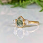 Moss Agate and Herkimer diamond engagement ring on a gold band, showcasing a pear-shaped Moss Agate with raw Herkimer diamonds.
