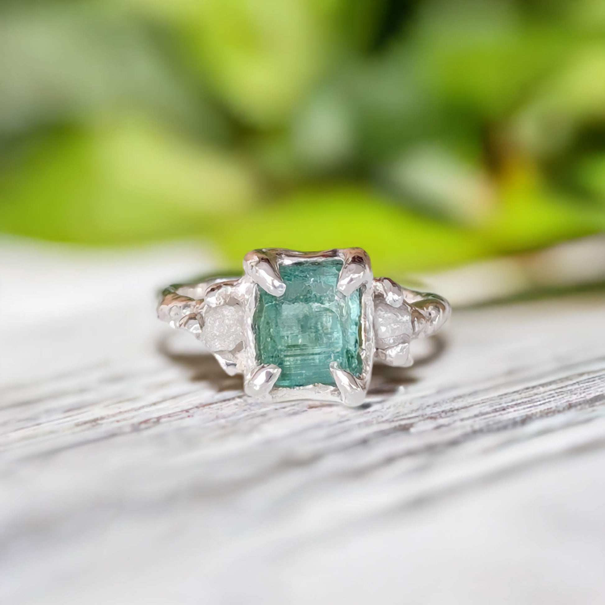 Raw emerald and diamond engagement ring in solid sterling silver with mint green stone, showcasing nature-inspired design.