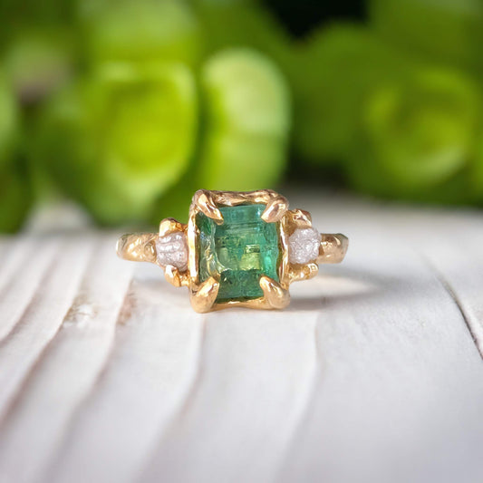 Raw emerald and diamond engagement ring in solid 14k gold with nature-inspired design, showcasing mint green emerald and two diamonds.