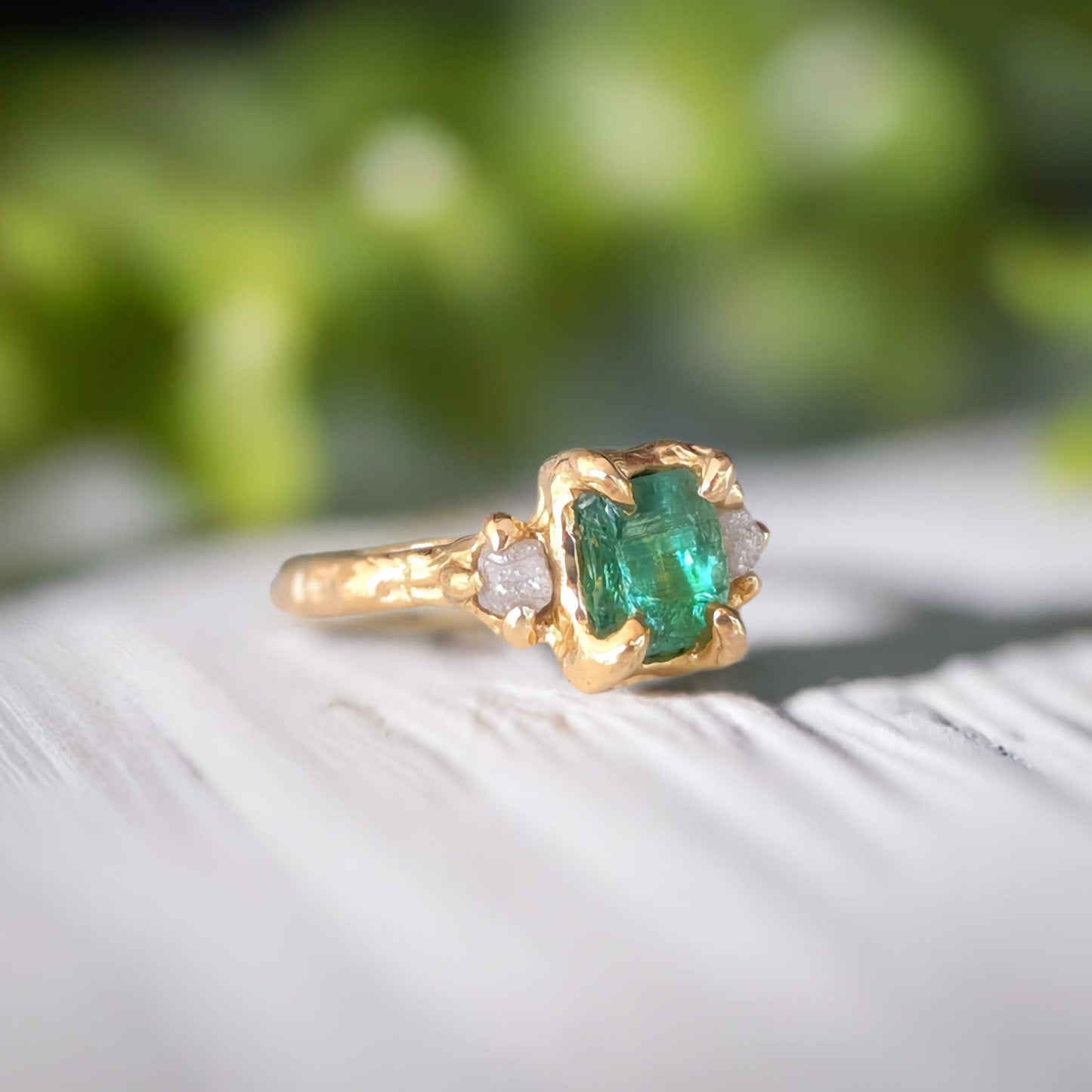 Raw emerald and diamond engagement ring in solid 14k gold, showcasing mint green emerald and two small raw diamonds.