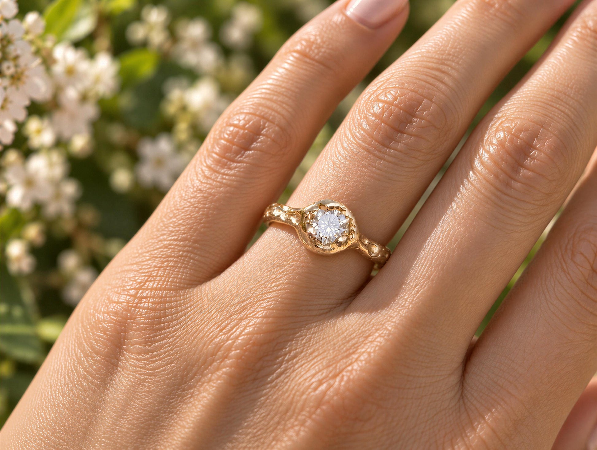 A close-up of a gold-textured engagement ring featuring a round Moissanite set in the center, worn on a woman's hand.