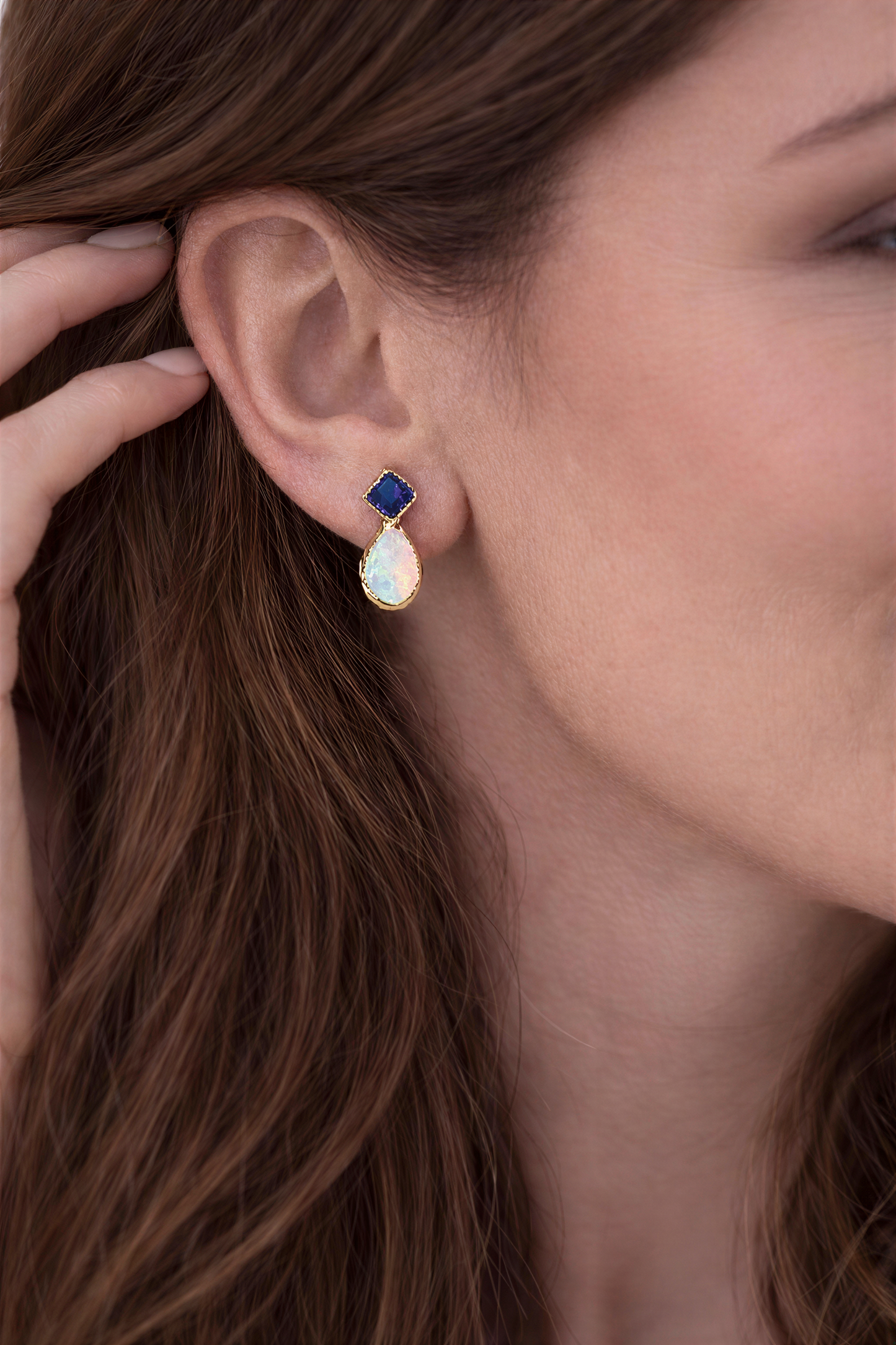 Blue Sapphire and Opal stud earrings in Gold worn by a woman, showcasing their dainty and elegant design.