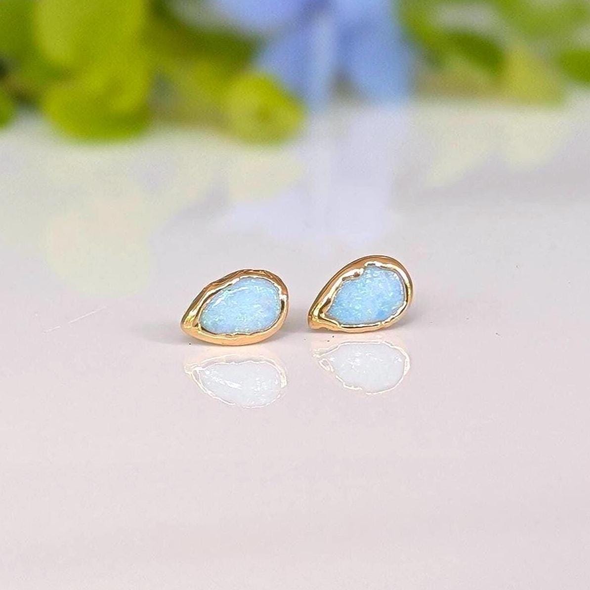 A pair of pear-shape white australian opal stud earrings in gold textured setting. The opals have lovely flashes of color.