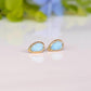 A pair of pear-shape white australian opal stud earrings in gold textured setting. The opals have lovely flashes of color.