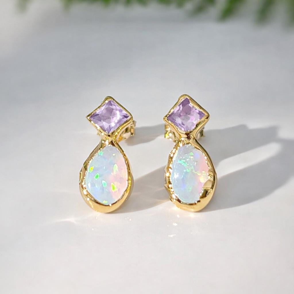 Gold earrings with light purple amethyst and teardrop-shaped opal stones on a light background
