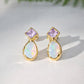 Gold earrings with light purple amethyst and teardrop-shaped opal stones on a light background