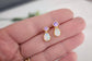 Opal and Amethyst gemstone stud earrings held in a hand with a blurred background