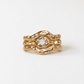 A gold ring with a large central diamond set in a unique, organic design.
