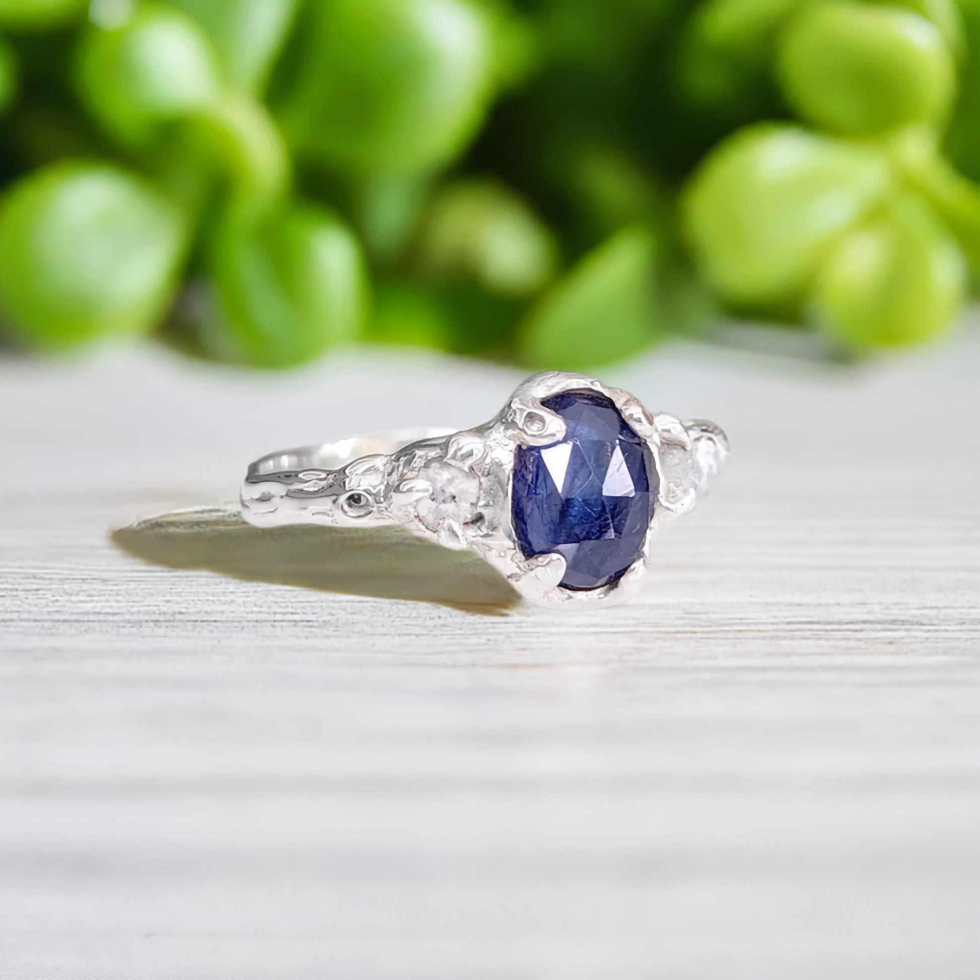Blue sapphire and raw diamond engagement ring in solid sterling silver with floral background.
