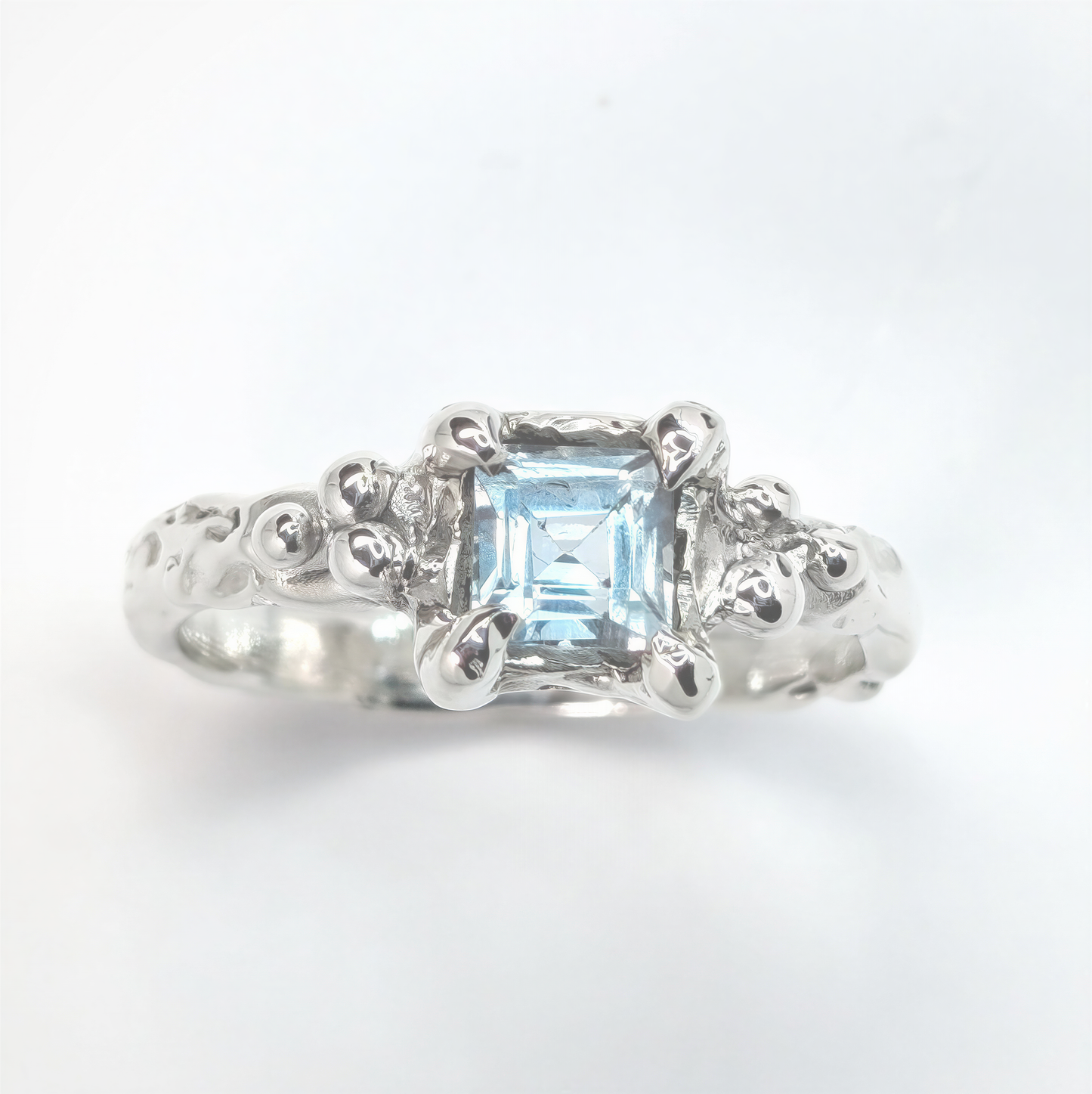 Handcrafted blue topaz engagement ring in sterling silver with organic textured band.