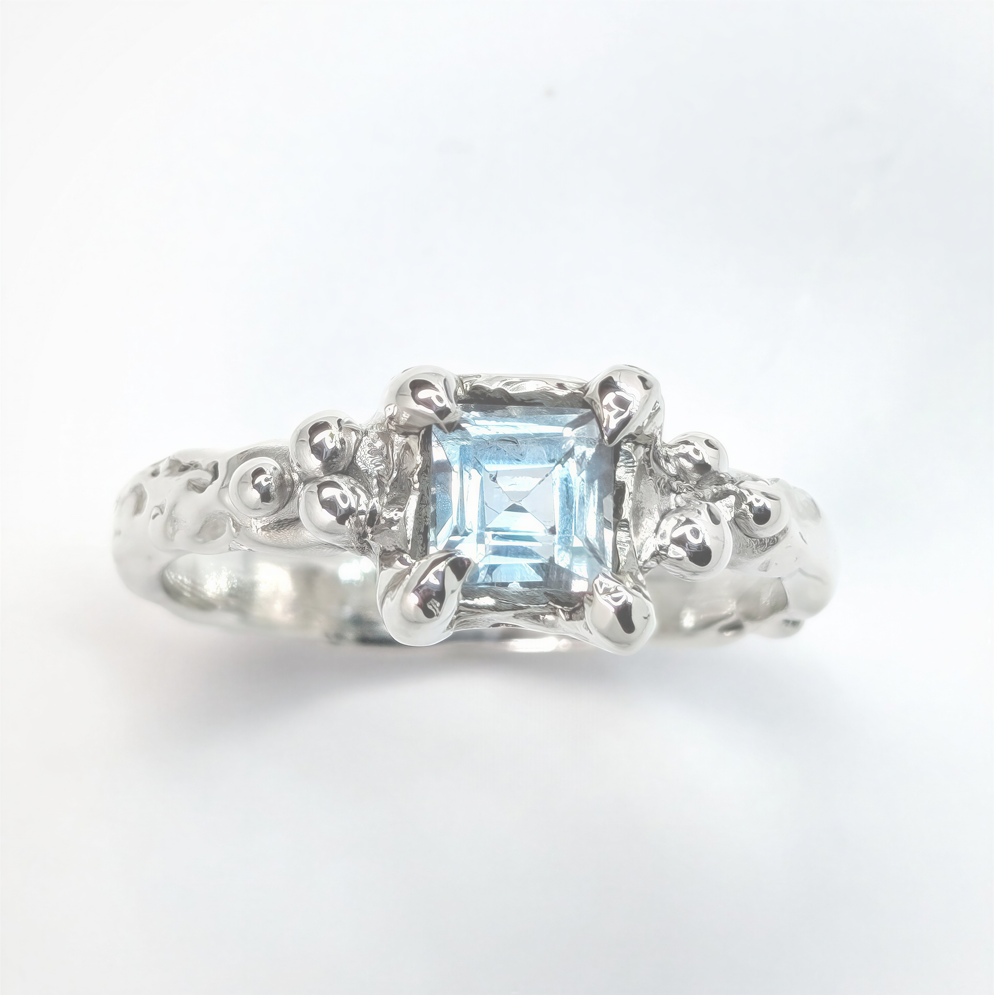 Handcrafted blue topaz engagement ring in sterling silver with organic textured band.