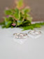 two silver rings with a large central stone, placed on a white surface with a blurred green plant in the background.
