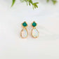 Pair of gold earrings with Emerald and opal stones on a light background