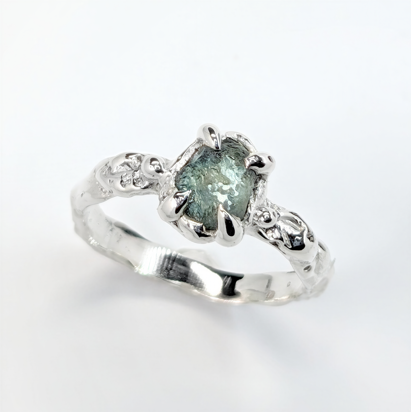 Side view of rustic silver Montana sapphire engagement ring showing organic molten textures