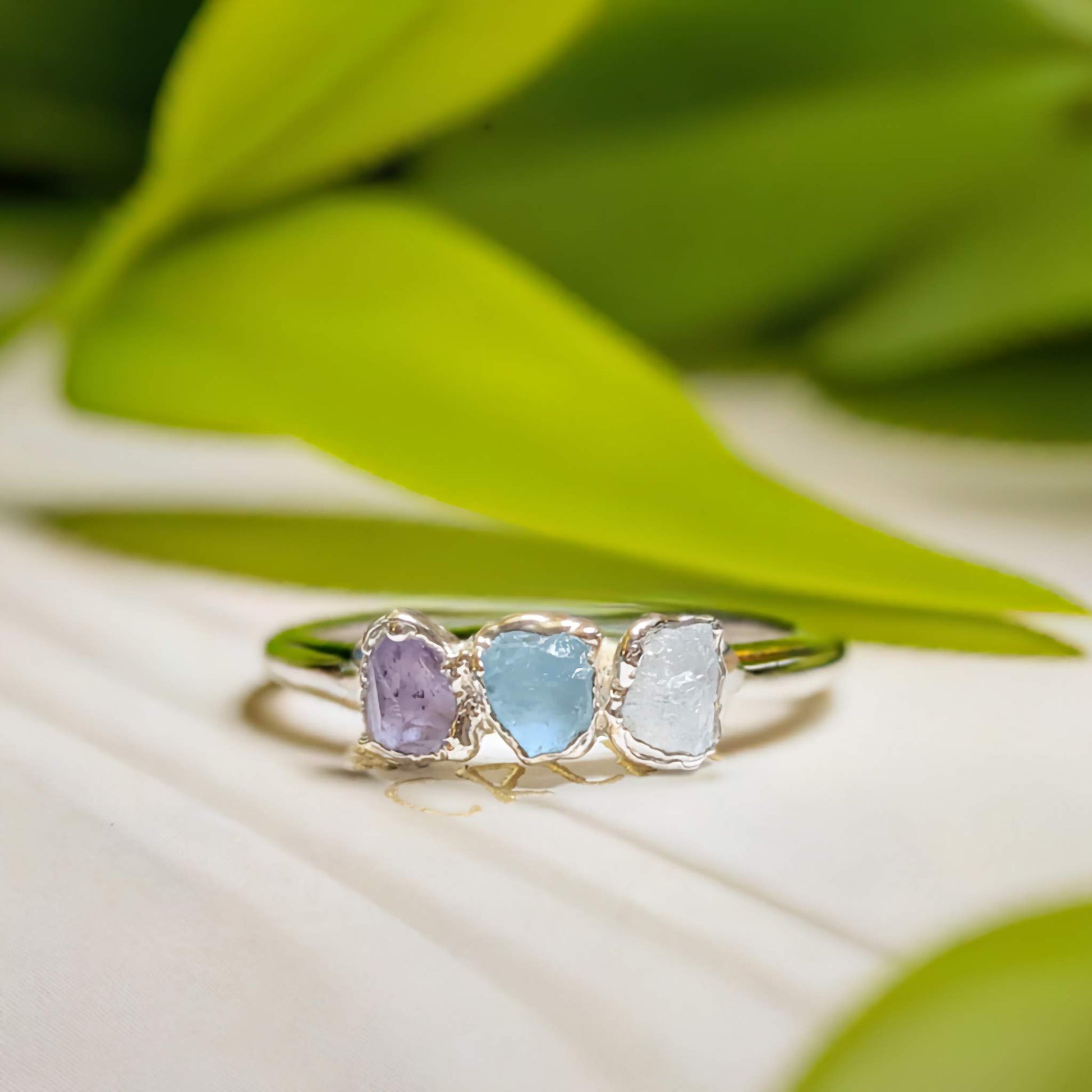 Handcrafted raw gemstone Mother's ring featuring three unique birthstones on a delicate silver band.