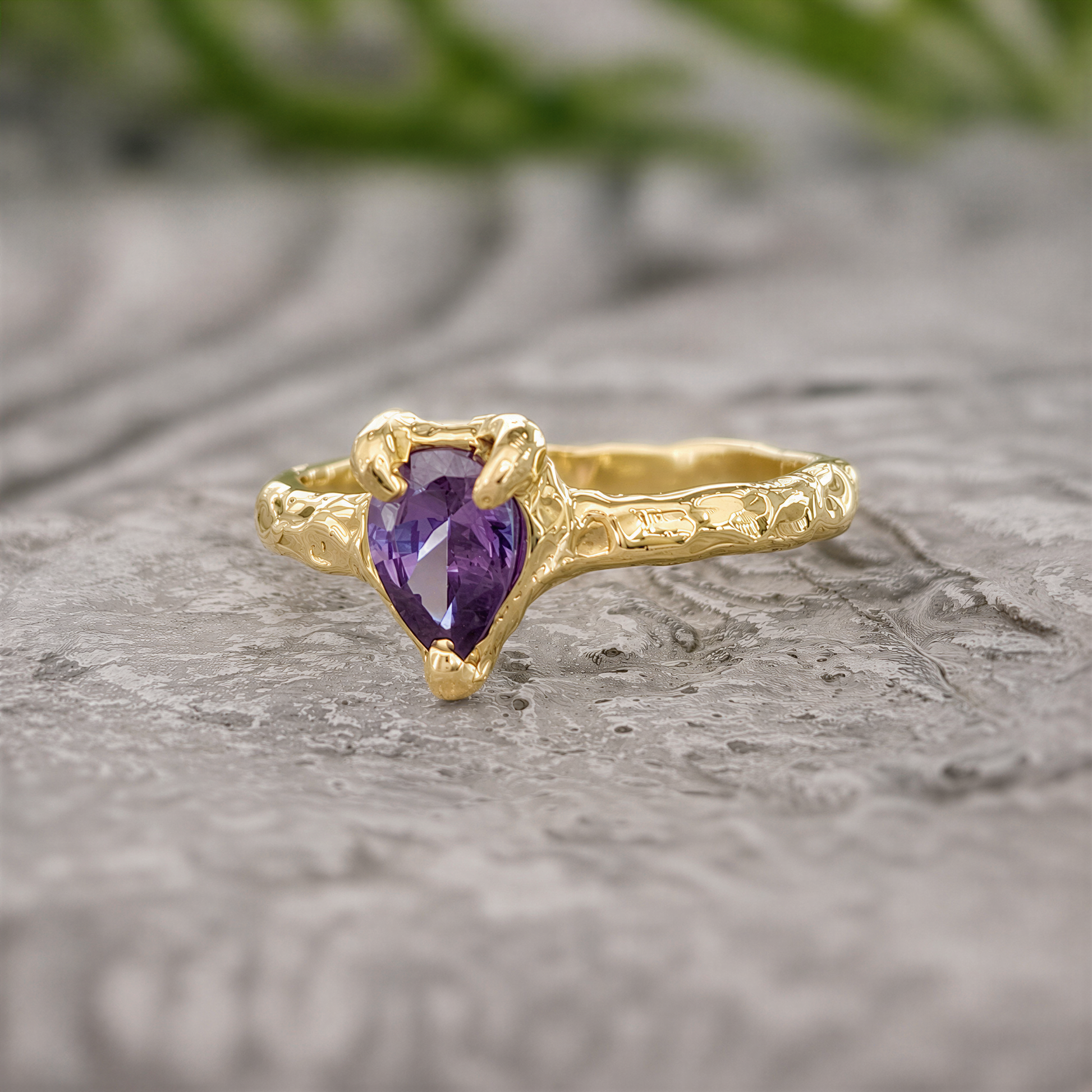 A Solid 14k Gold textured ring featuring a pear-shaped amethyst - set on a stone surface