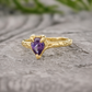 A Solid 14k Gold textured ring featuring a pear-shaped amethyst - set on a stone surface