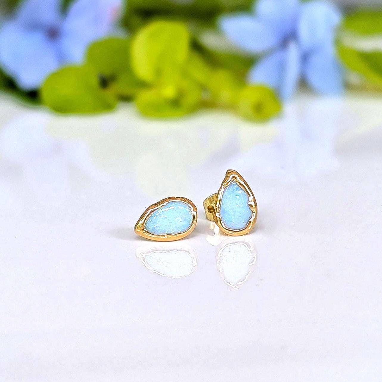 A pair of pear-shape white australian opal stud earrings in gold textured setting. The opals have lovely flashes of color.