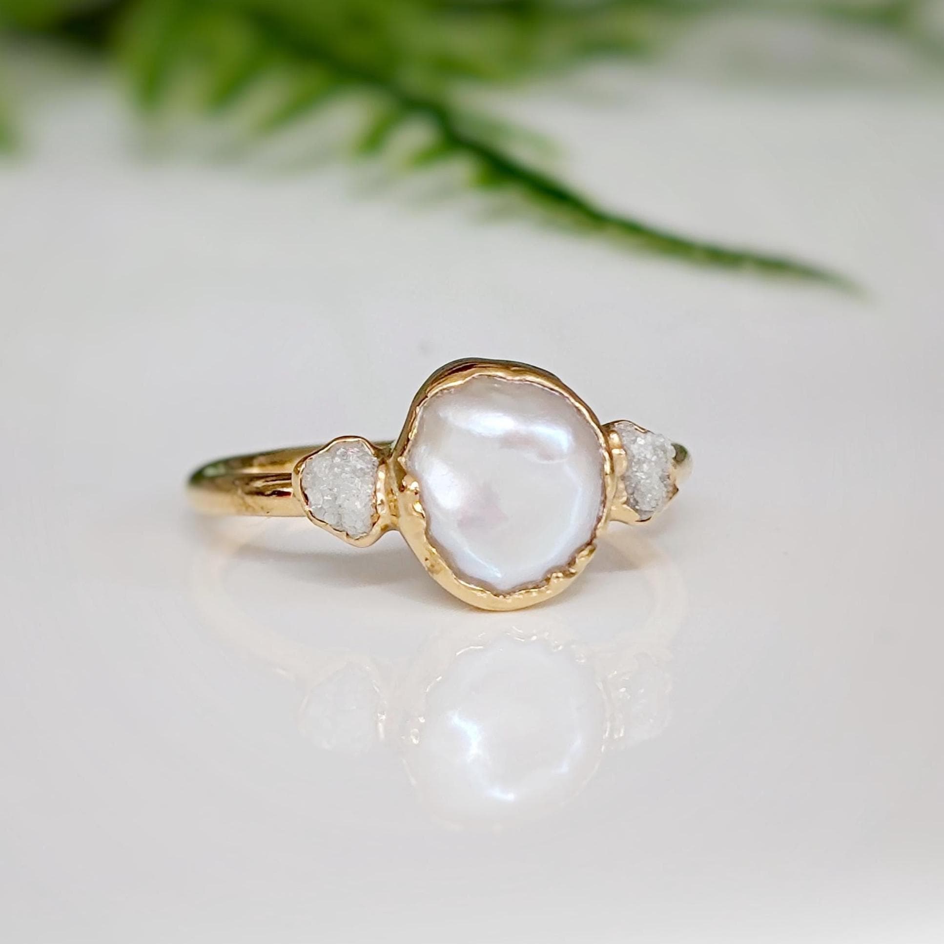 Elegant freshwater pearl and raw diamond engagement ring with gold band, showcasing rustic charm and romantic allure.