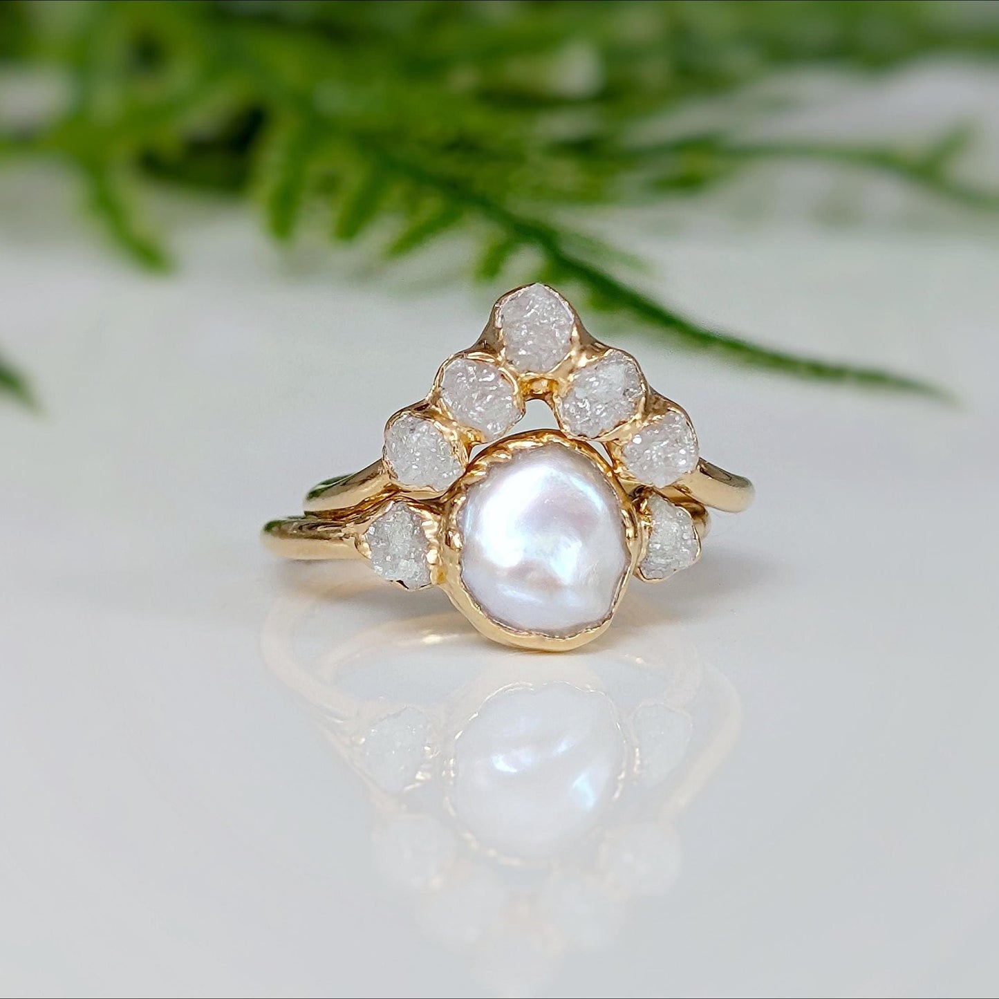 Freshwater pearl and raw diamond engagement ring with gold setting, showcasing a creamy pearl and rustic diamonds.