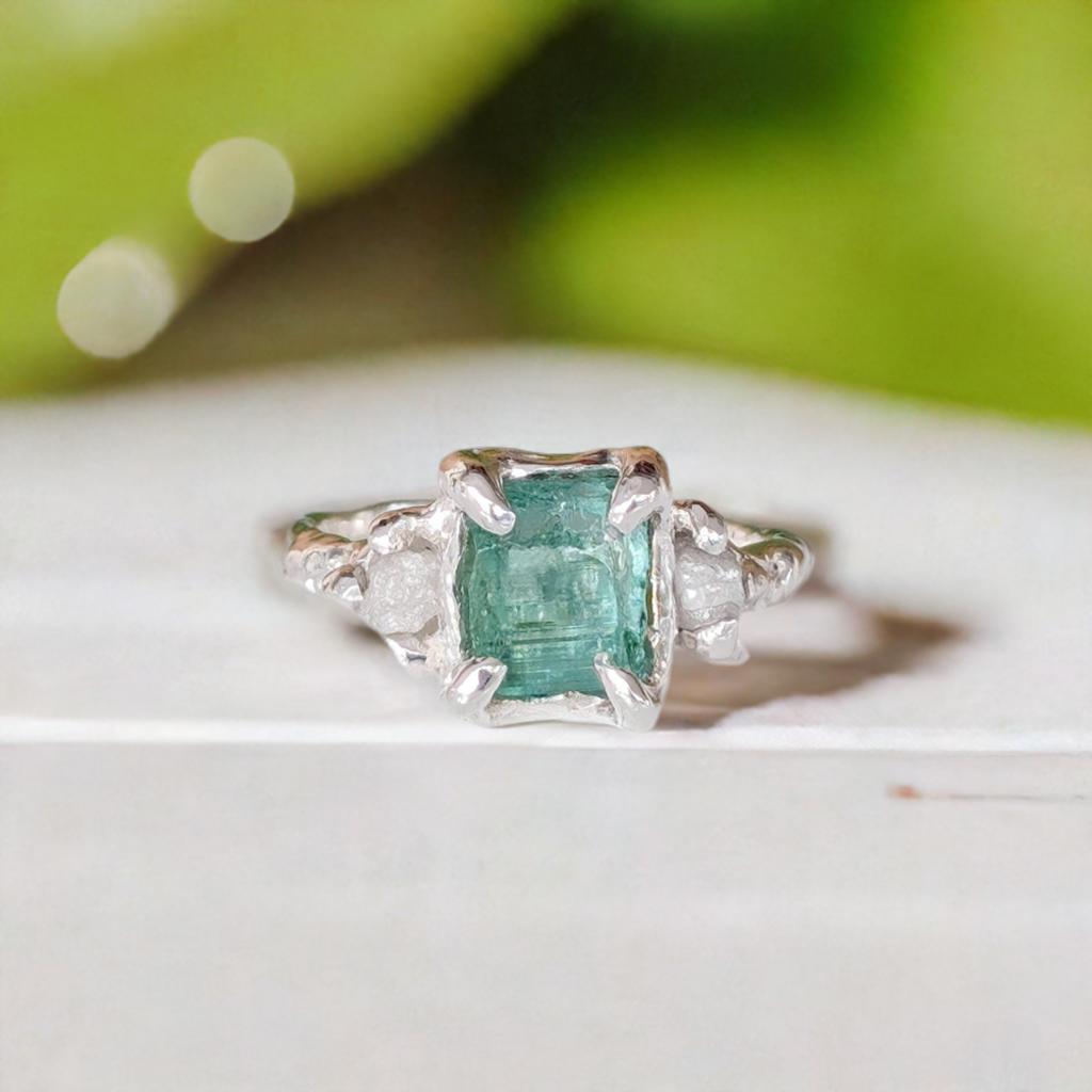 Raw emerald and diamond engagement ring in solid sterling silver, showcasing a mint green emerald and small diamonds.