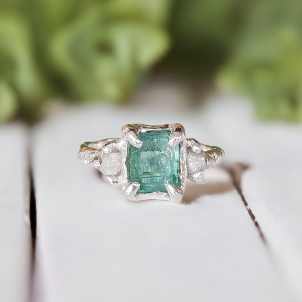 Raw emerald and diamond engagement ring in solid sterling silver with mint green emerald and textured finish.