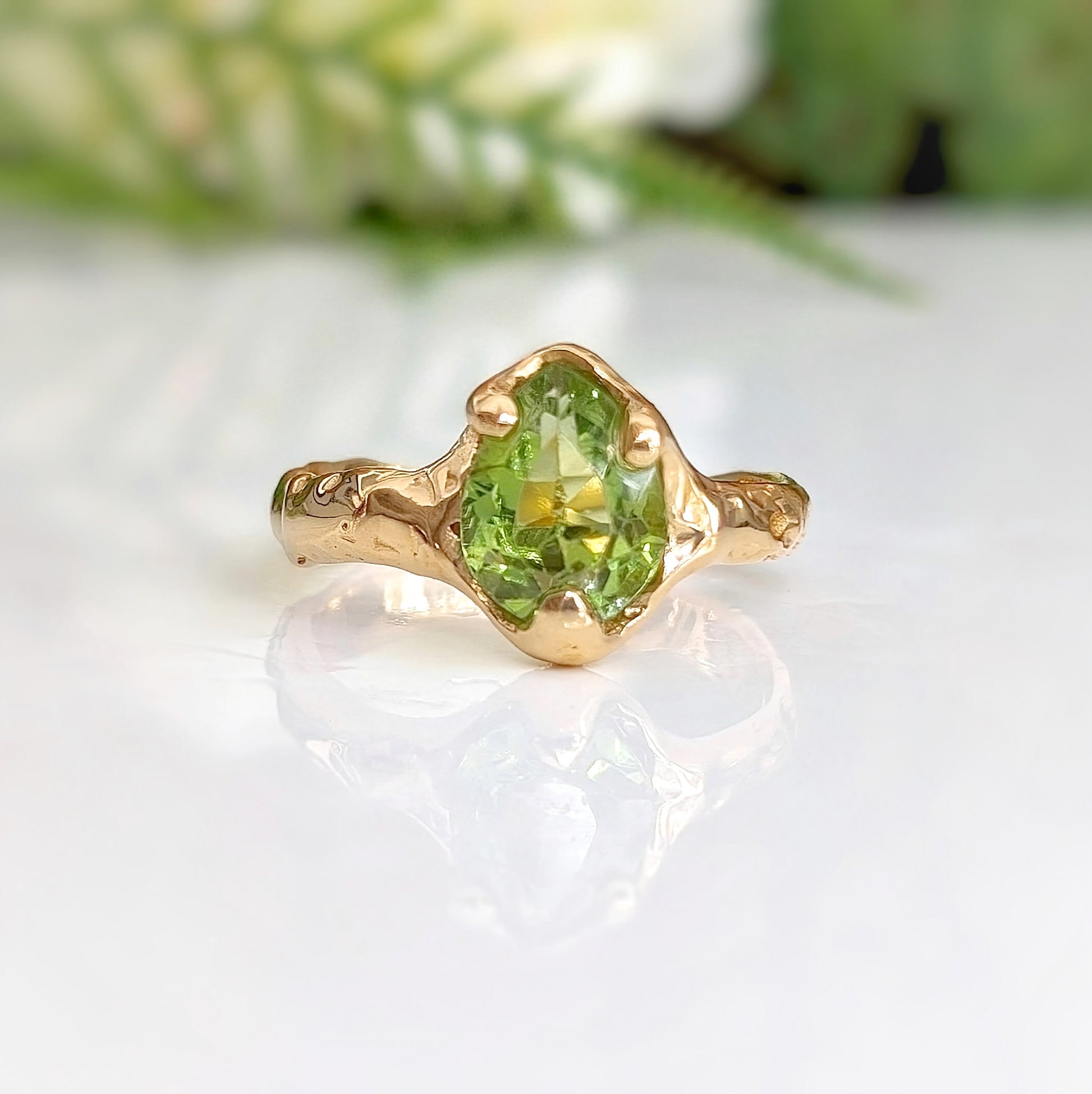 Handcrafted Peridot ring in solid 14k gold, featuring an organic textured band and vibrant green gemstone.