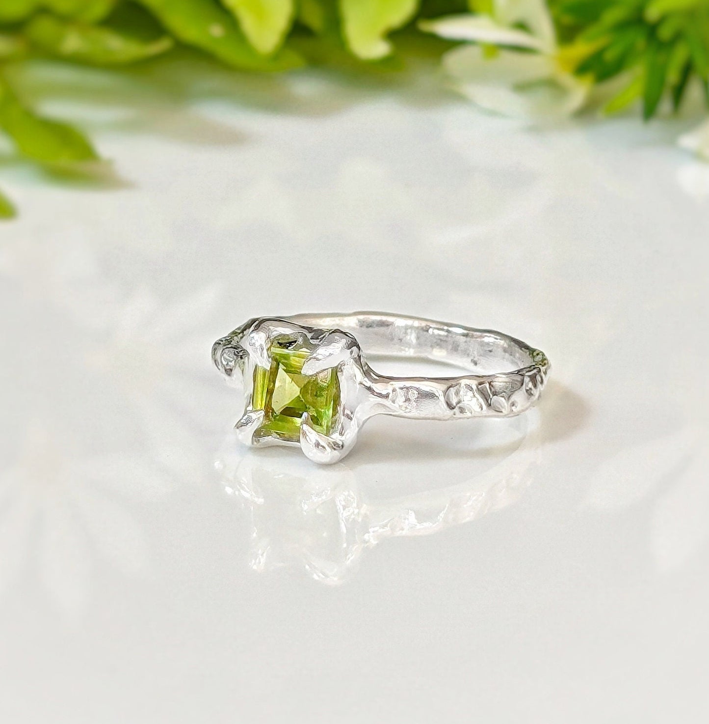 Handcrafted solid silver Peridot ring with organic textured band and princess-cut green crystal.