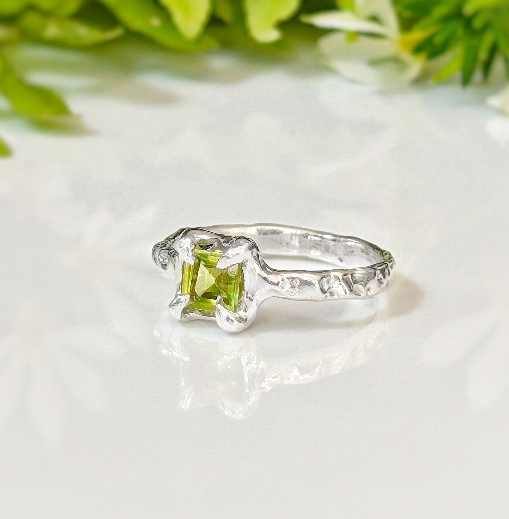 Handcrafted solid silver Peridot ring with organic textured band and princess-cut green crystal.