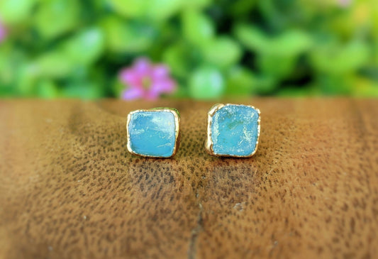 Raw Peruvian opal stud earrings with gold settings, showcasing shades of blue and green, perfect for ocean-inspired jewelry.